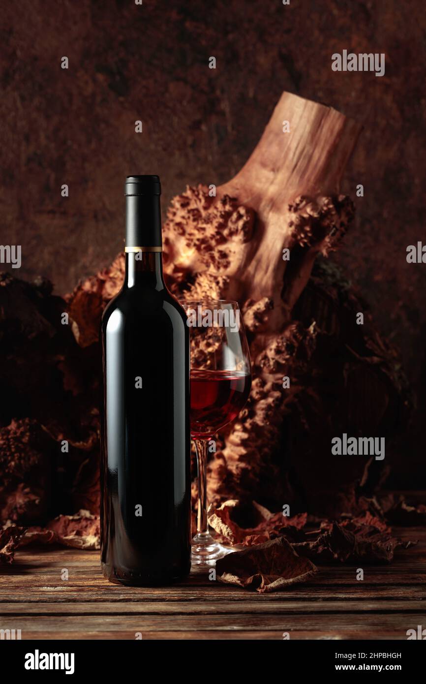 Bottle and glass of red wine on an old wooden table. In the background ...