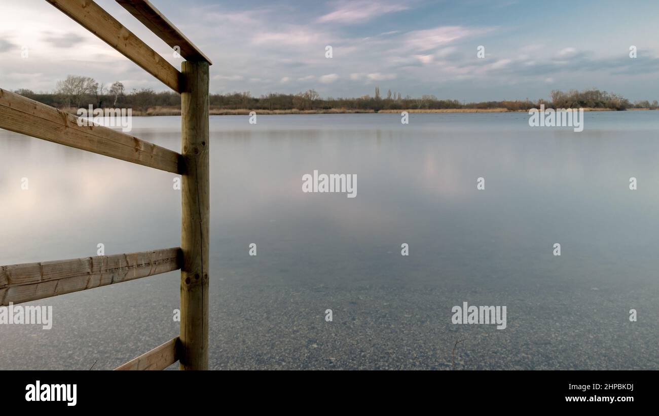Wooden fence on the shore of a lake in the blue hour Stock Photo - Alamy