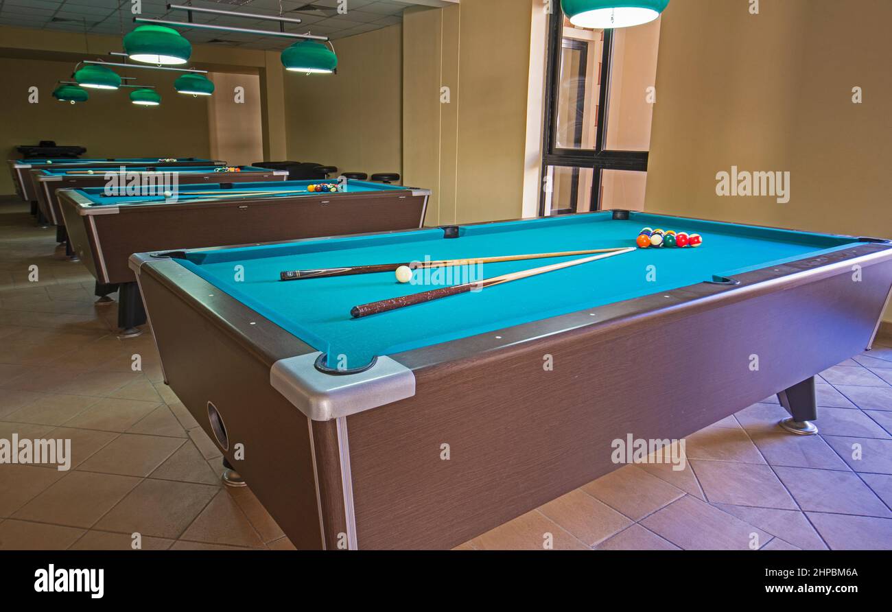 Row of pool billiards tables with balls and cues in leisure club sports hall Stock Photo