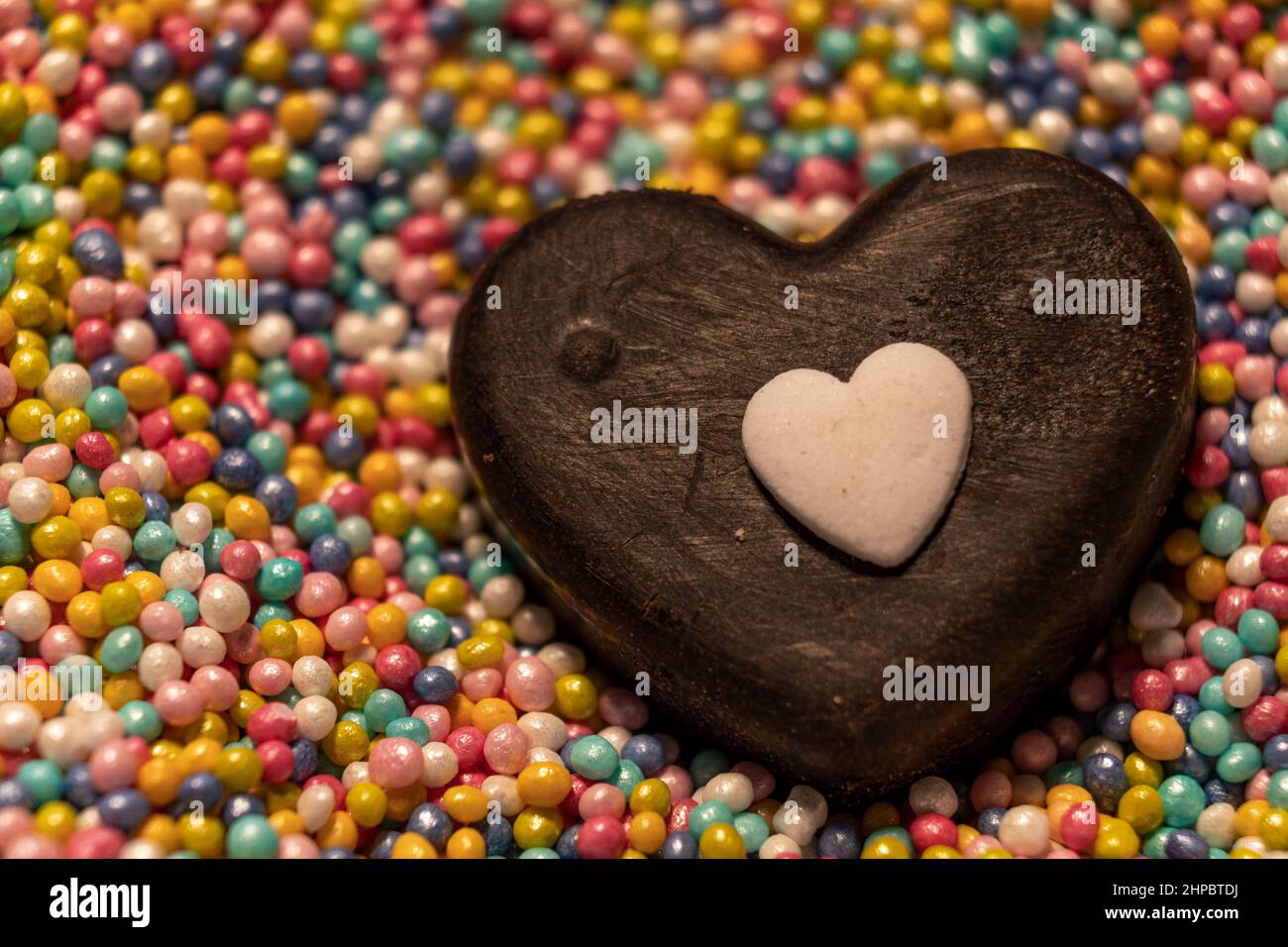 Ein Herz aus selbstgemachter Schokolade Kontrastreich auf Liebesperlen. Stock Photo