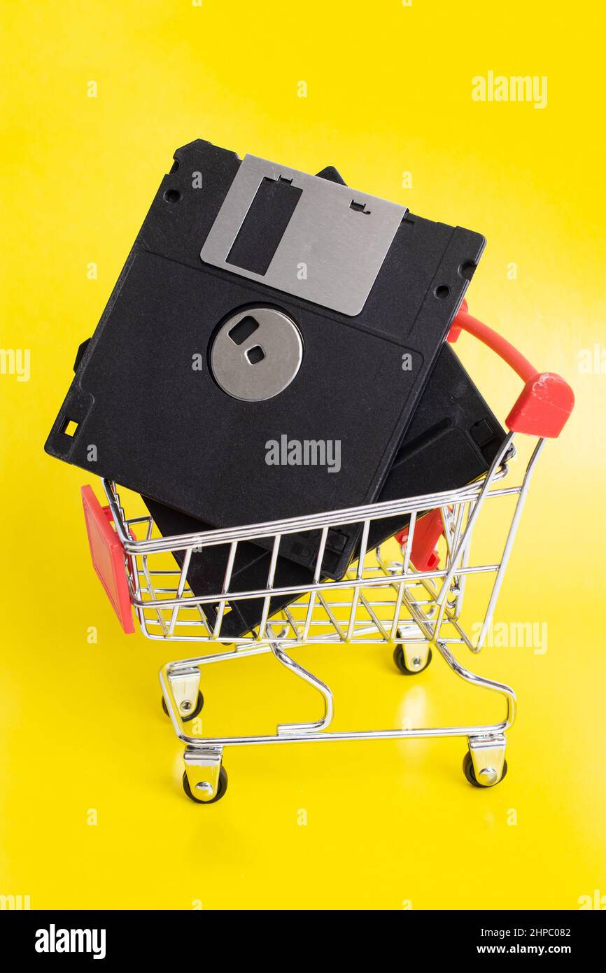 Floppy disks in shopping cart on yellow background Stock Photo