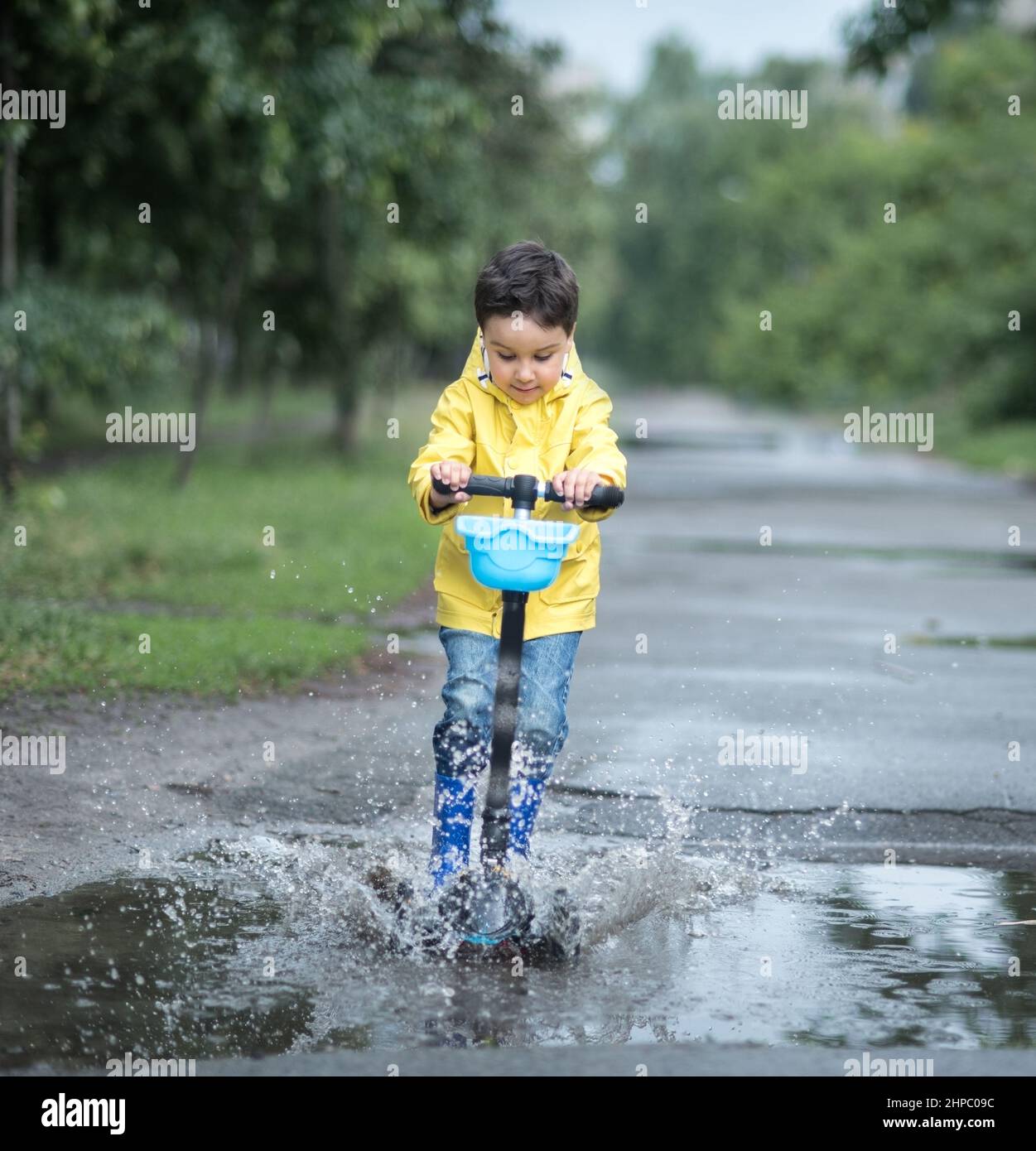 Little boy in raincoat and rubber boots playing in puddle Stock Photo ...