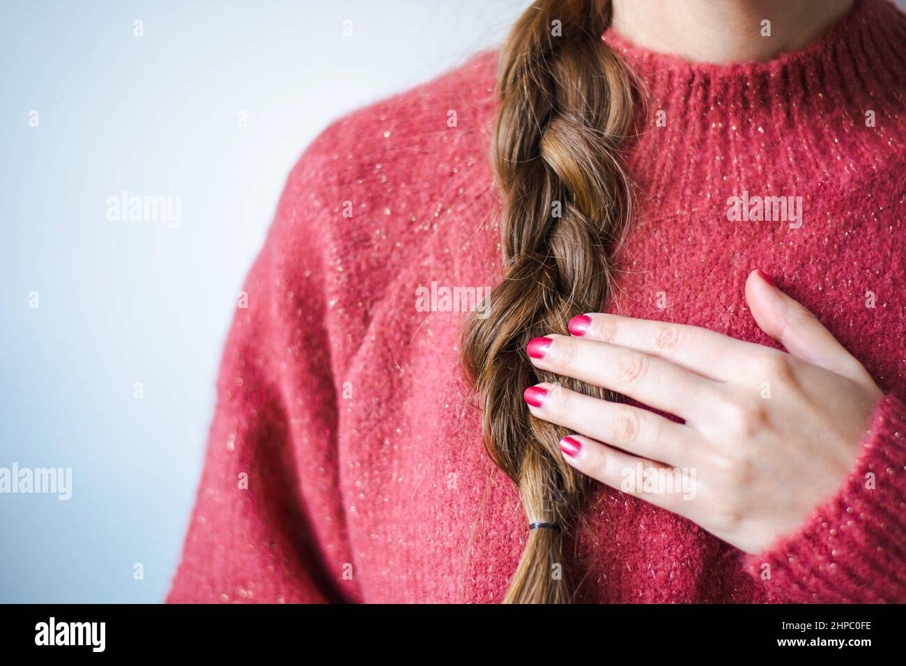 Woman with braid and nail polish wearing a pink warm soft glitter winter sweater Stock Photo