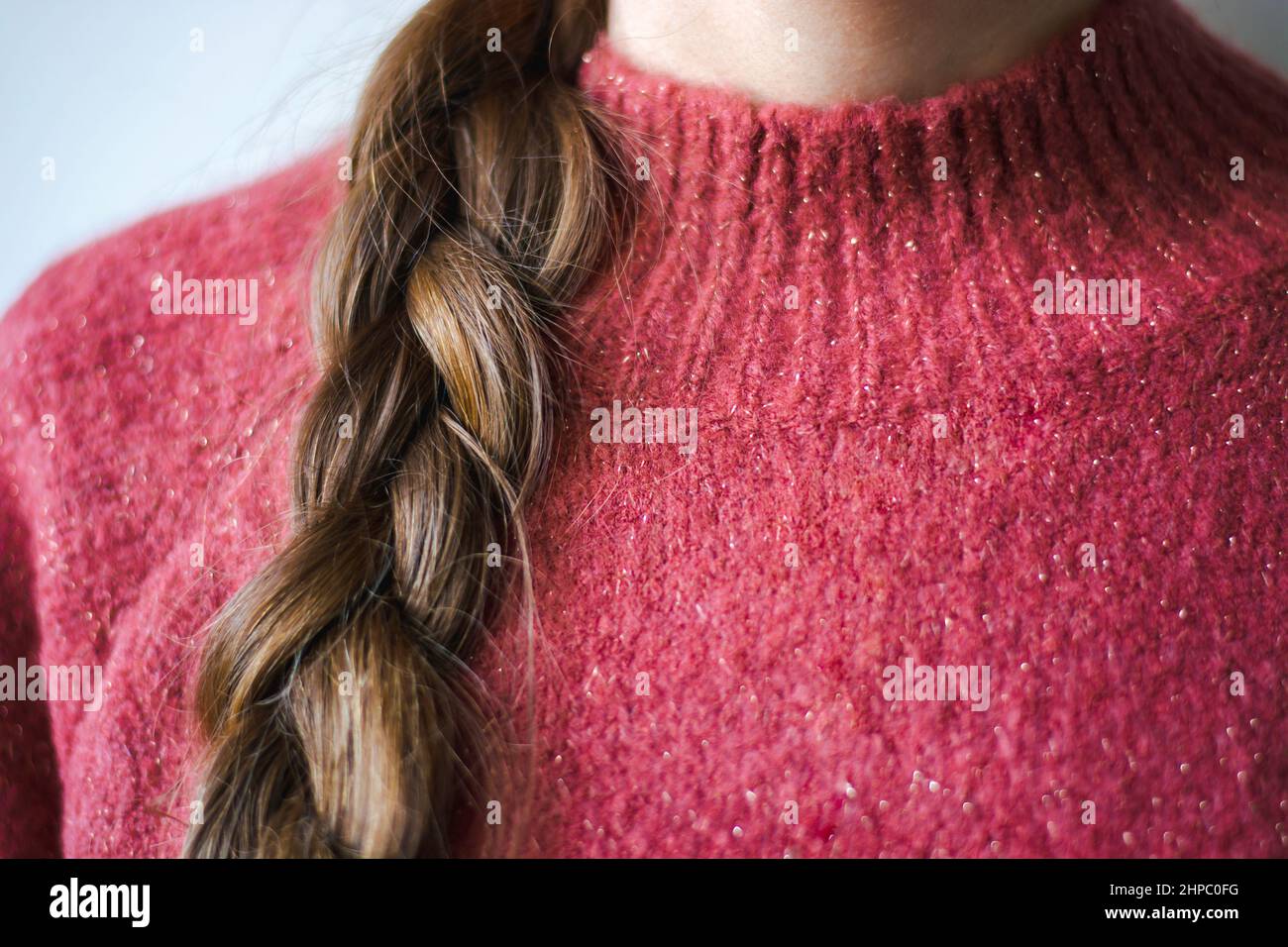 Close-up woman with braid wearing a pink warm soft glitter winter sweater Stock Photo