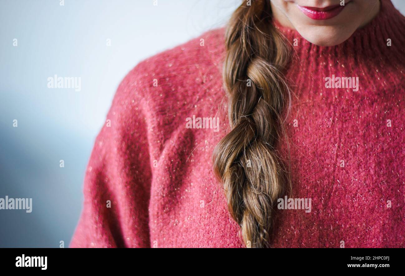 Woman with braid and lipstick wearing a pink warm soft glitter winter sweater Stock Photo