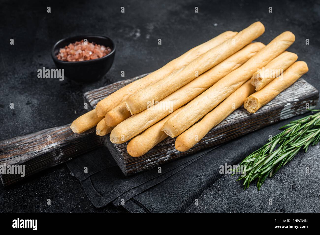 Italian grissini or salted bread sticks on wooden board. Black bakground. Top view Stock Photo