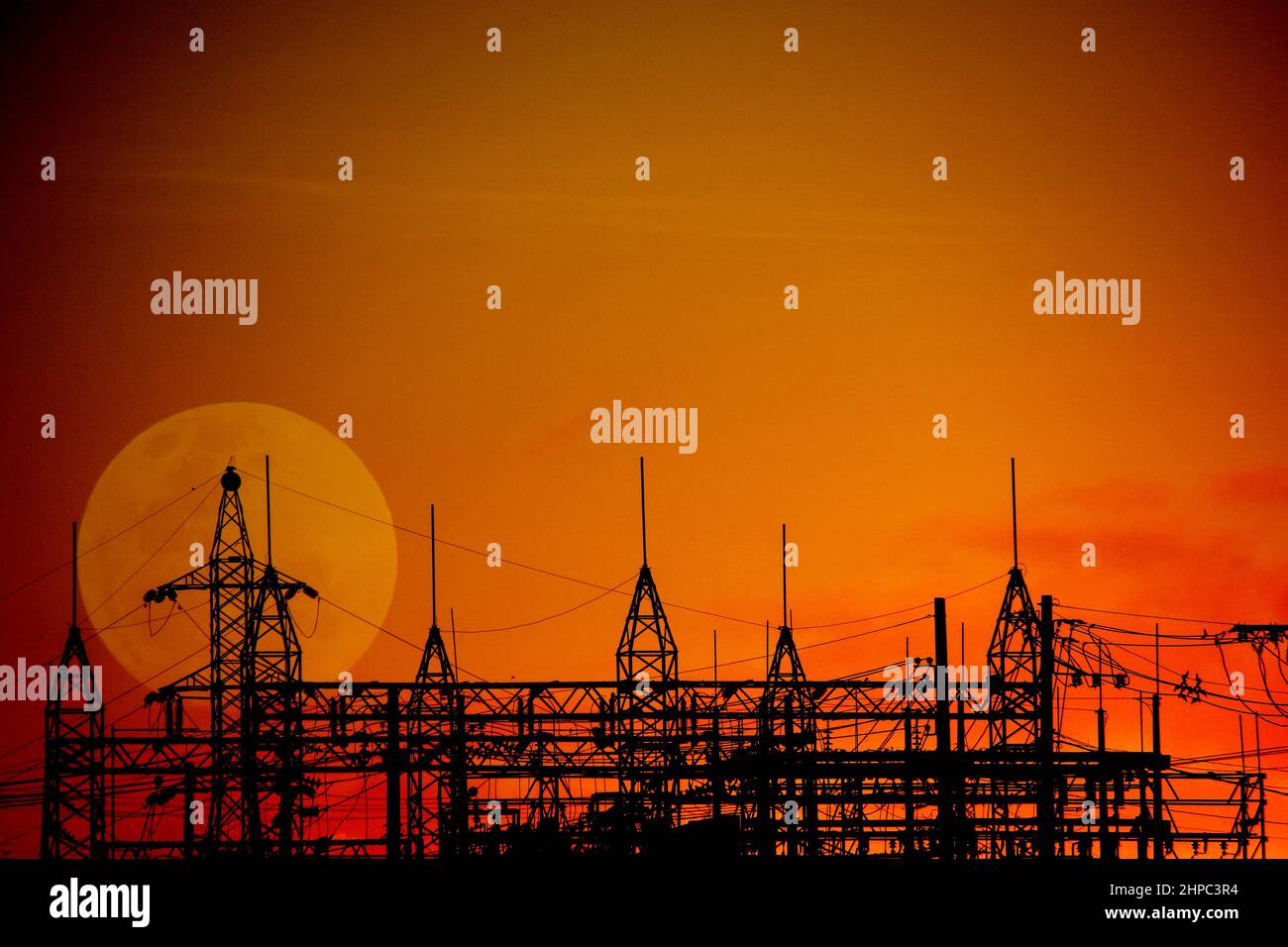 Electricity distribution substation in backlight and warm late afternoon colors. Metal structure of energy distribution Stock Photo