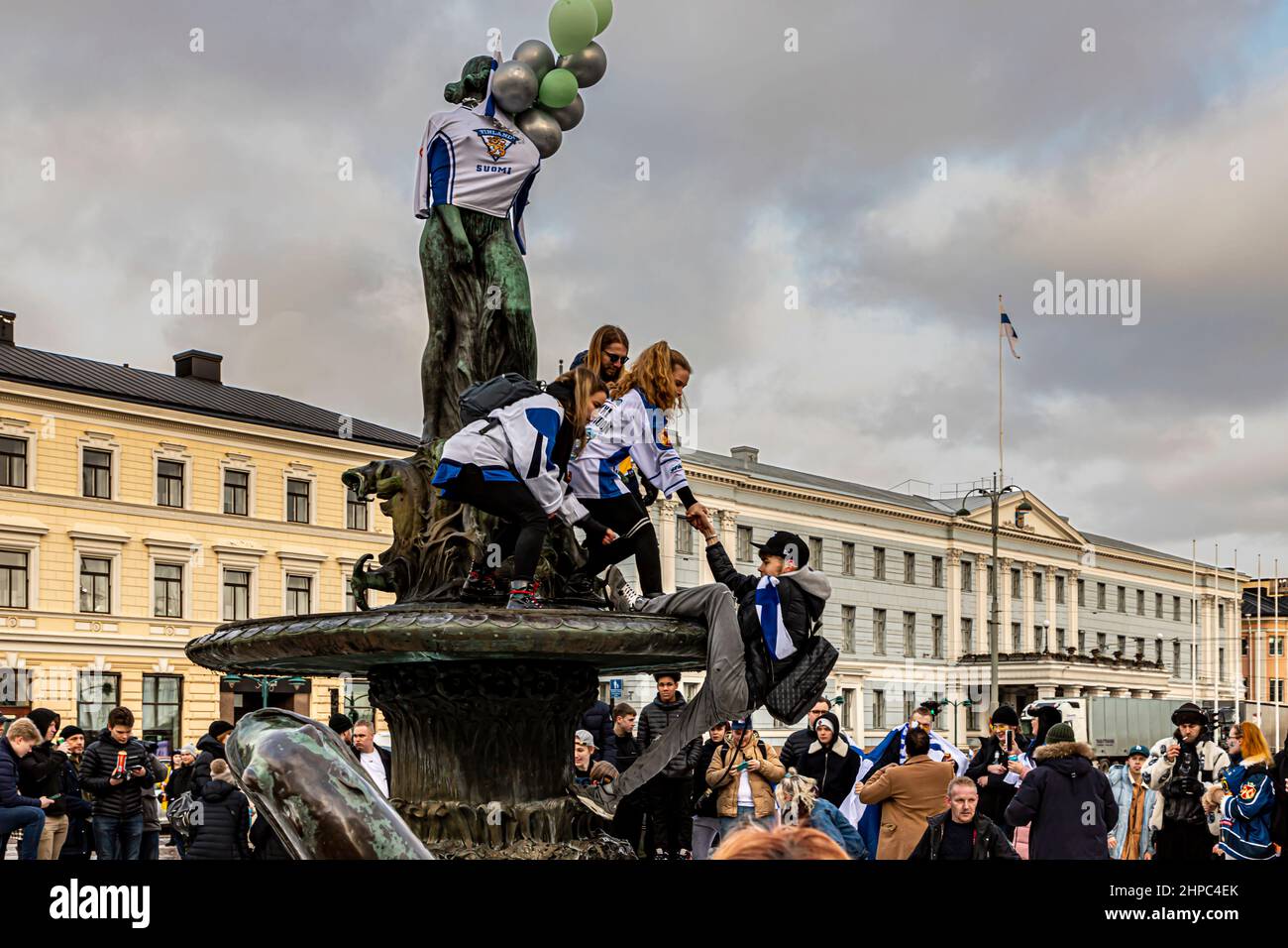 Hockey fans on the Havis Amanda statue in the Helsinki Market Square, helping another fan climb the statue. Stock Photo