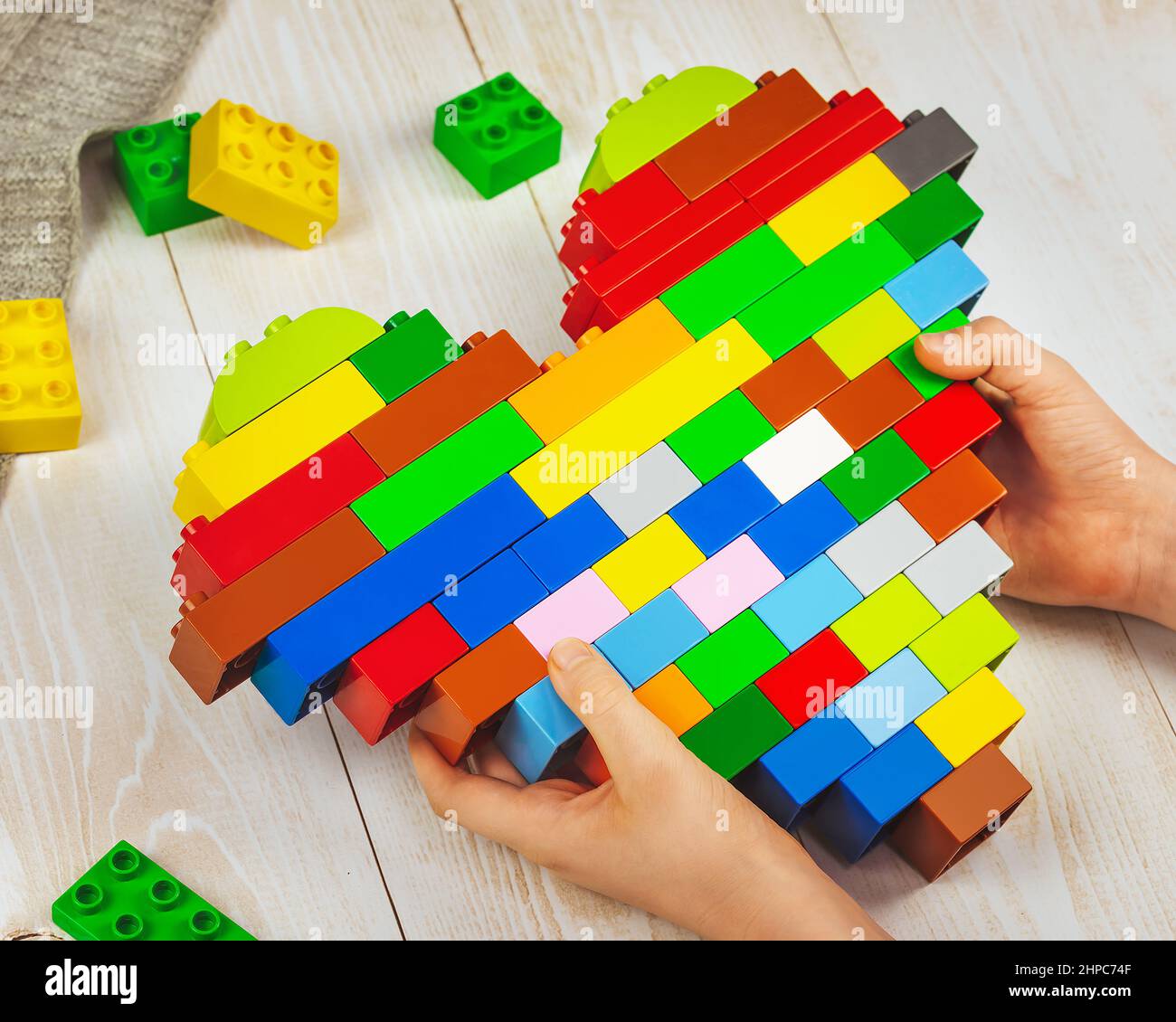 A child is holding a heart made of lego bricks in his hands. A child's  gift. The concept of love, family and a gift to parents Stock Photo - Alamy