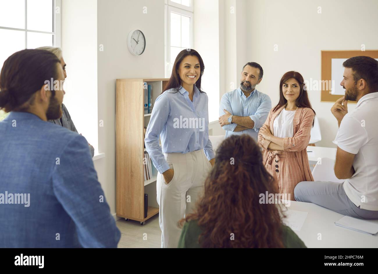 Happy young businesswoman or business coach having a meeting with a group of people Stock Photo