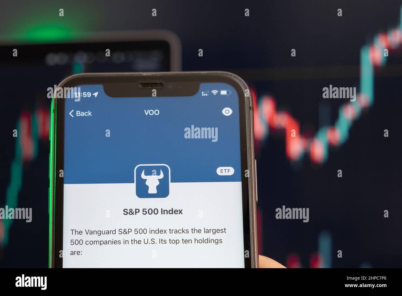 S and P 500 Index stock price uptrend with graphs on the background. Man hands holding a smartphone with logo on the screen, February 2022, San Francisco, USA. Stock Photo