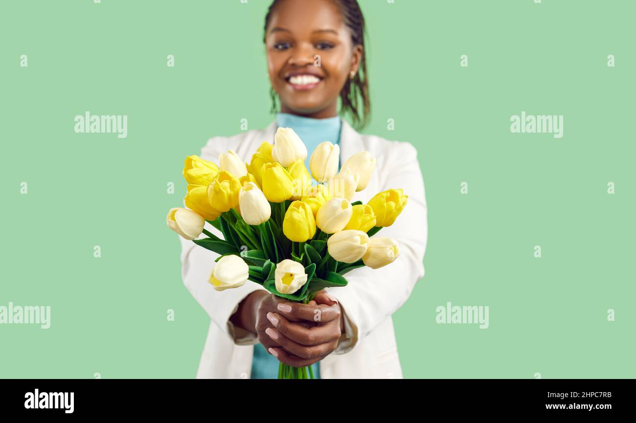 Happy young black woman holding a beautiful bouquet of fresh yellow and white tulips Stock Photo