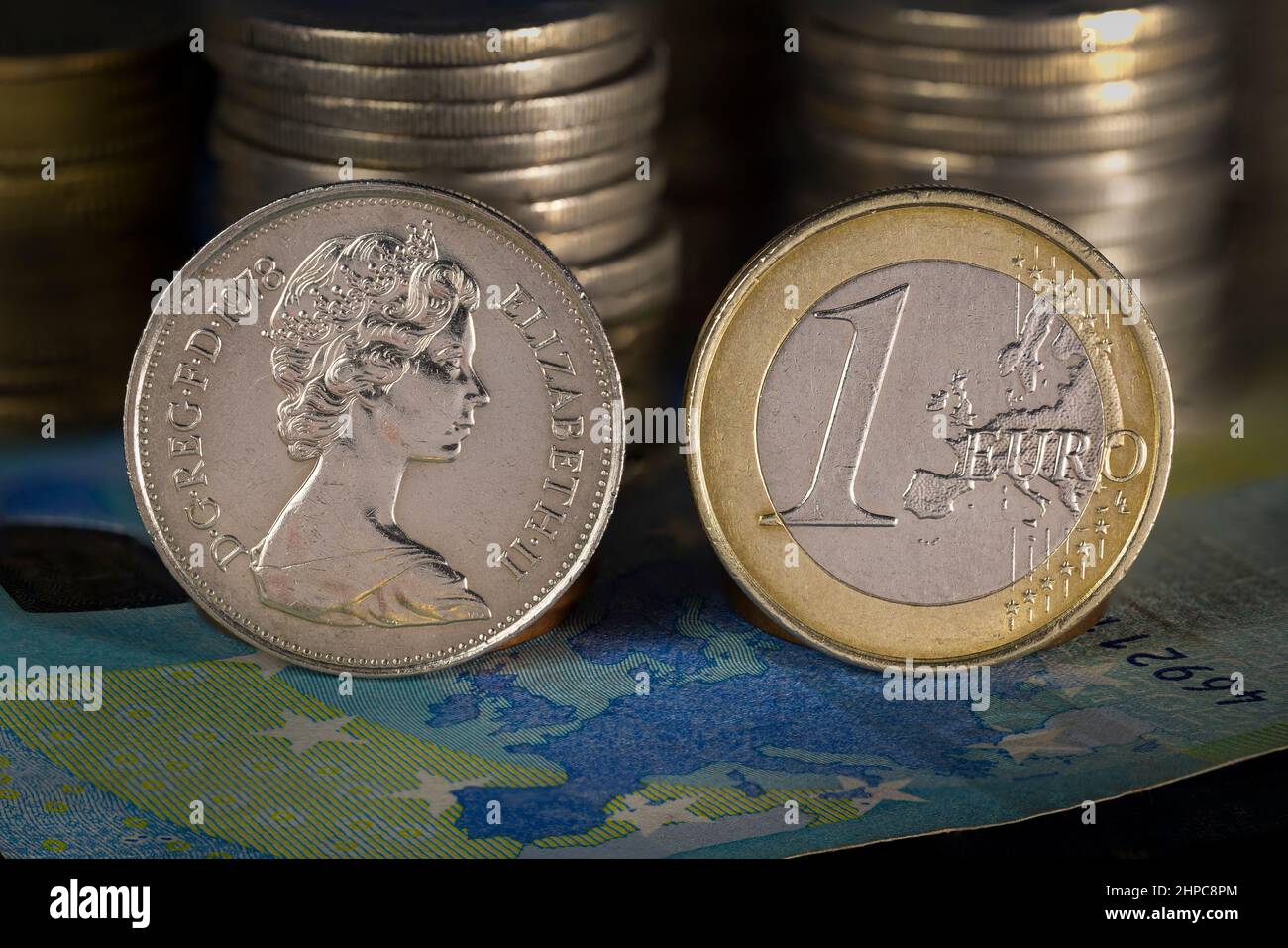 Queen Elizabeth and Euro Coins standing on Europe map printed on 20 Euro Bank Note Stock Photo