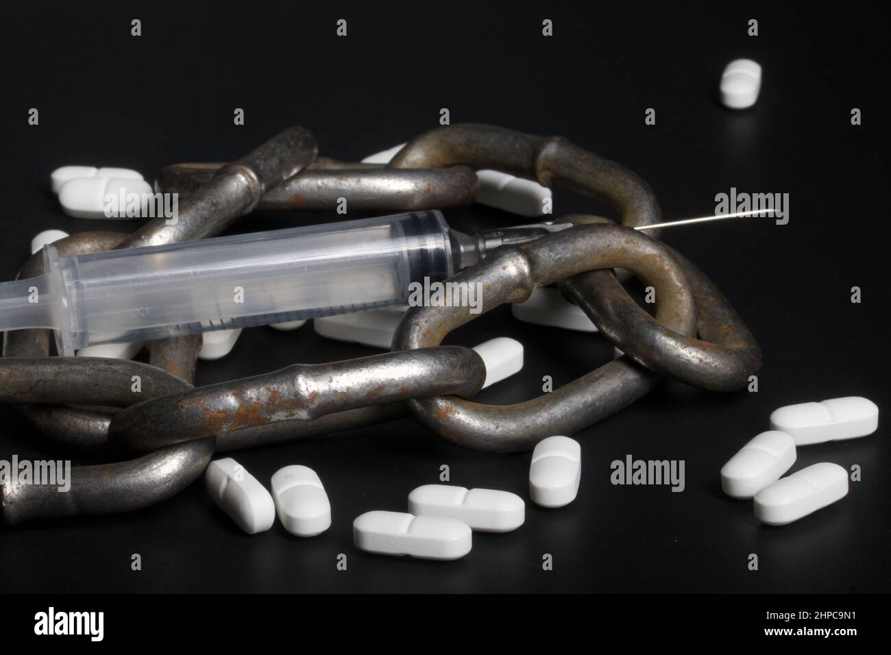 White tablets. Medical syringe and metal chain. Symbol of drug ...
