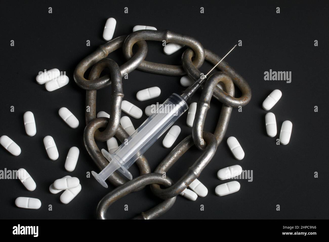 White tablets. Medical syringe and metal chain. Symbol of drug ...