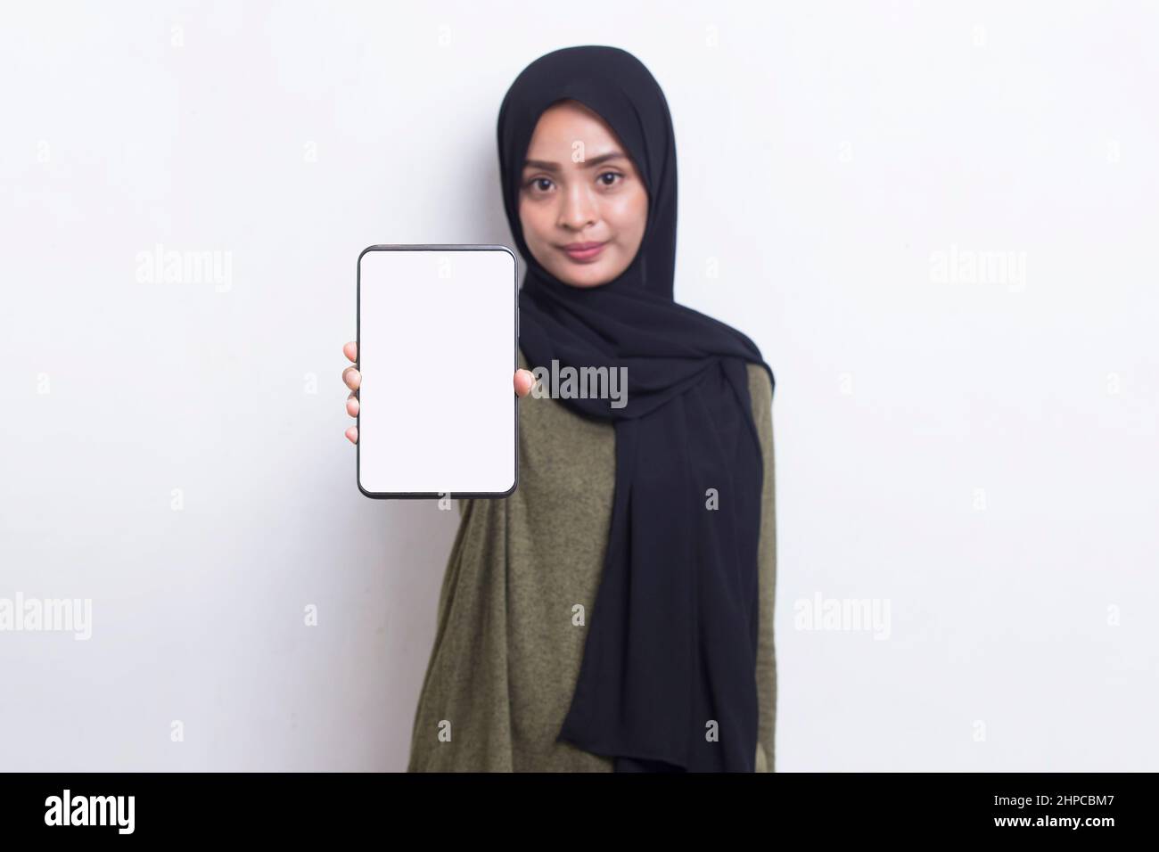 Happy Asian woman in hijab demonstrating mobile cell phone. Portrait of ...