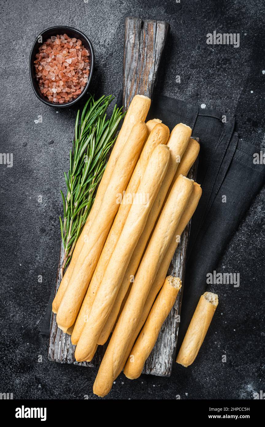 Italian grissini or salted bread sticks on wooden board. Black bakground. Top view Stock Photo
