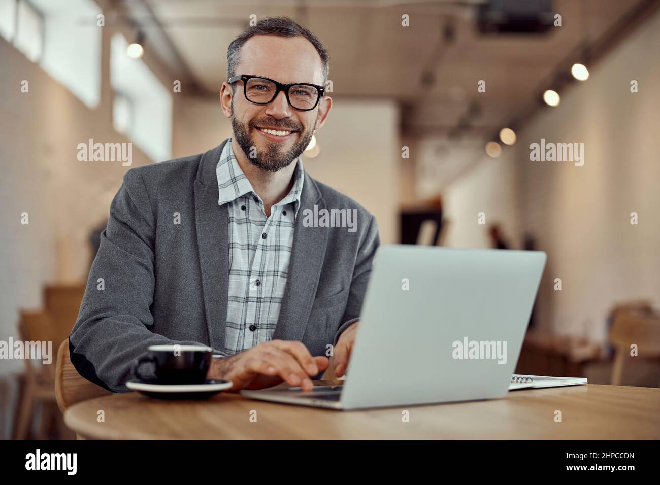 Cheerful bearded man using laptop in cafe Stock Photo