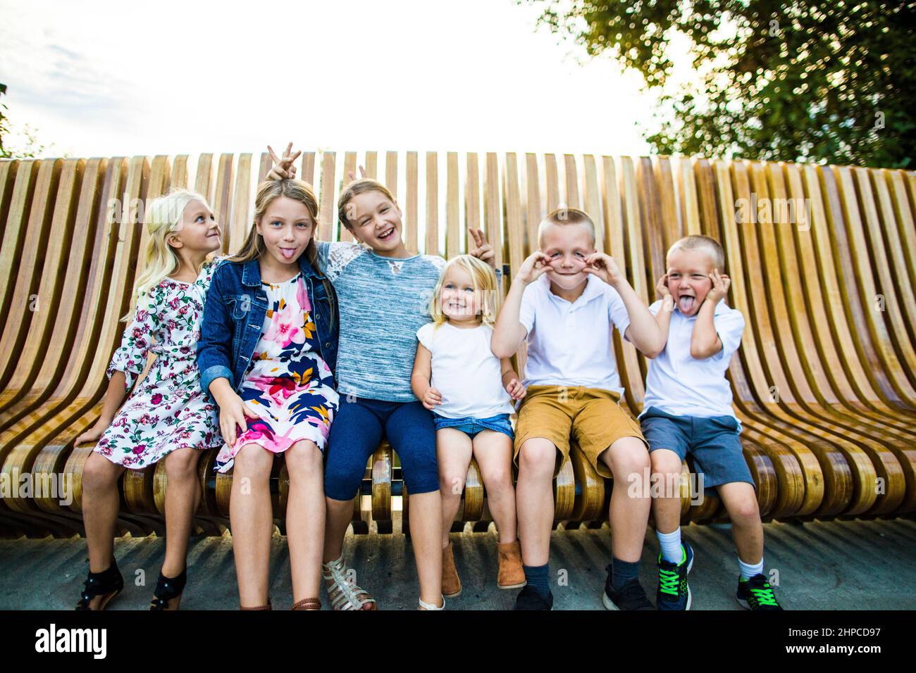 Six siblings making funny faces together outdoors. Stock Photo