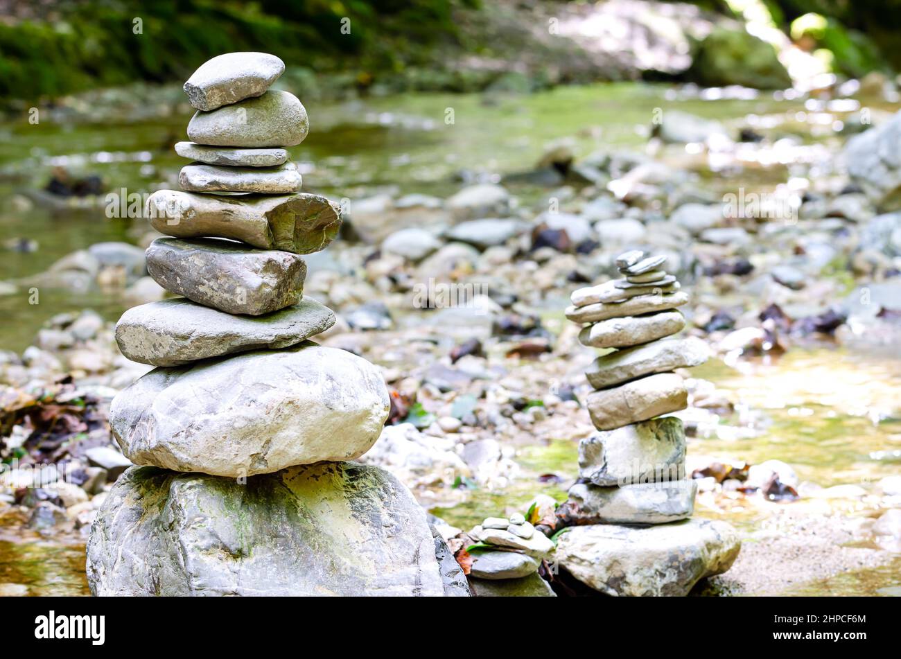 Two rock stacks in a creek bed. Piles of stacked rocks, balancing on big rocks in a bed of a wild stream. Rocks laid flat upon each other. Stock Photo