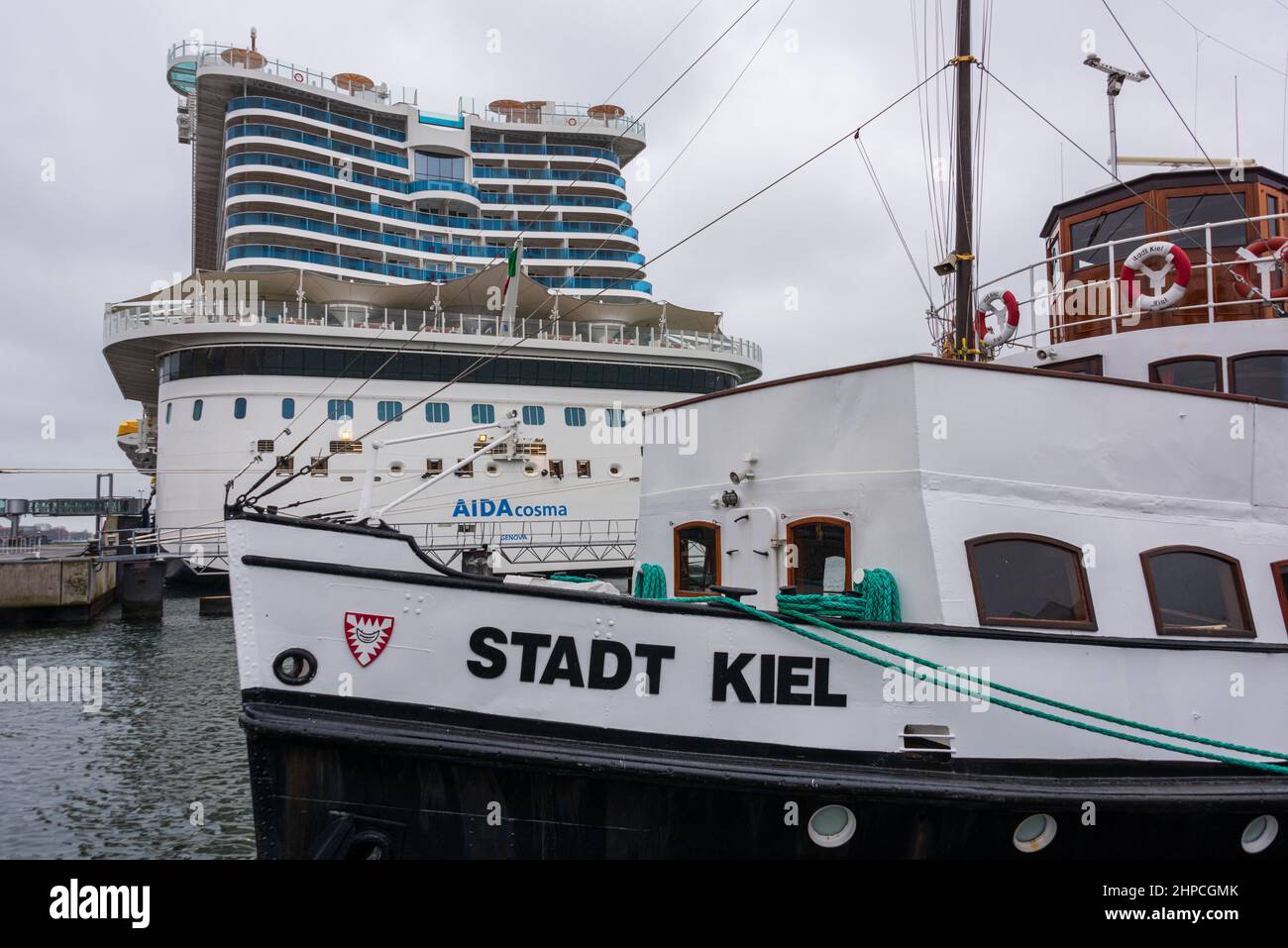 Die Heckpartie des Kreuzfahrtschiffes AIDAcosma am Ostseekai an einem Regnerischen Januartag. Im Vordergrund das Fahrgastschiff Stadt Kiel Stock Photo