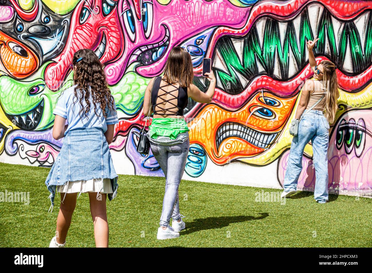 Miami Florida Wynwood Art District artwork wall visitors women friends posing teen teens teenage teenager teenagers,youth culture friends adolescent,resident residents girl girls,taking photo Stock Photo
