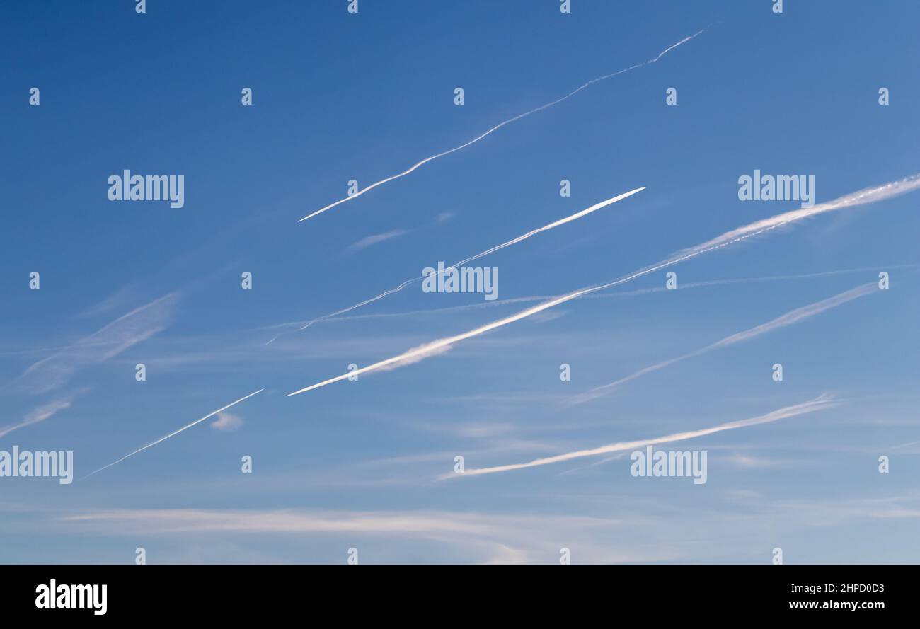 Contrails - a flying transport planes with white condensation trails in the blue sky Stock Photo