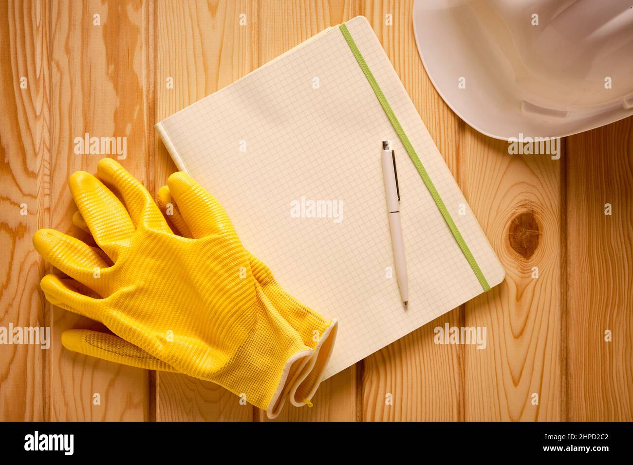 White hardhat, yellow gloves and blank notepad with pen Stock Photo