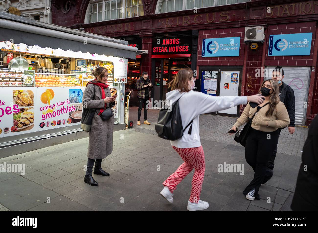 Arms open to greet a friend on London's Oxford Street. Picture taken by tube station in front of a street food vendor. Stock Photo