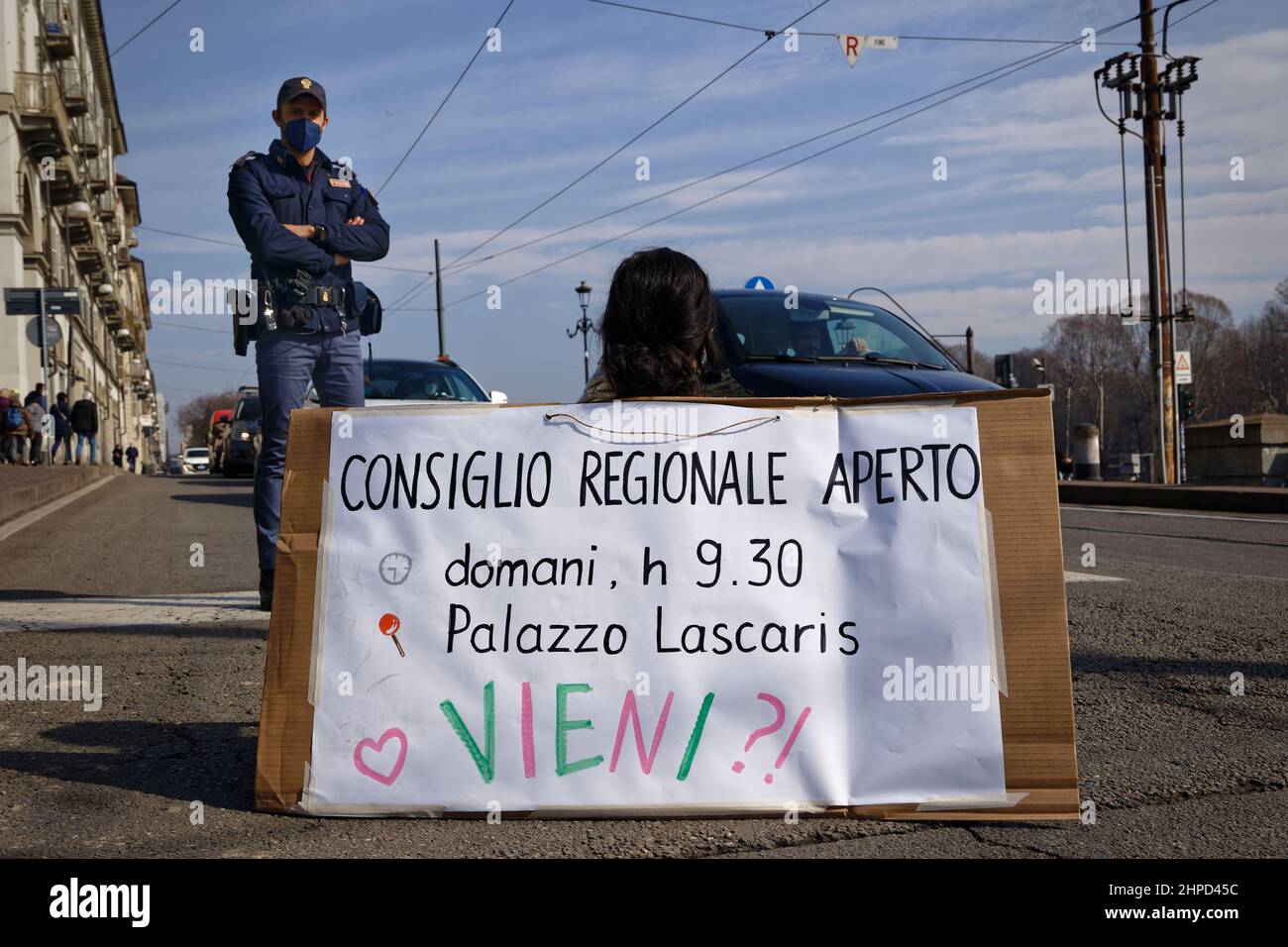 Turin, Italy. 20th Feb, 2022. Activists of Extinction Rebellion protest to denounce the inertia of the Piedmont Region towards the climate crisis. An activist sitting on the street shows placards to raise awareness of the climate emergency. Credit: MLBARIONA/Alamy Live News Stock Photo