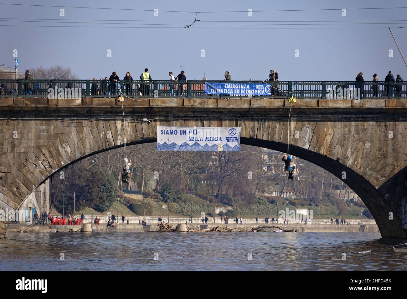 Turin, Italy. 20th Feb, 2022. Activists of Extinction Rebellion protest to denounce the inertia of the Piedmont Region towards the climate crisis. Two Extinction Rebellion activists descend in harness from a bridge over the River Po to display a protest banner. Credit: MLBARIONA/Alamy Live News Stock Photo