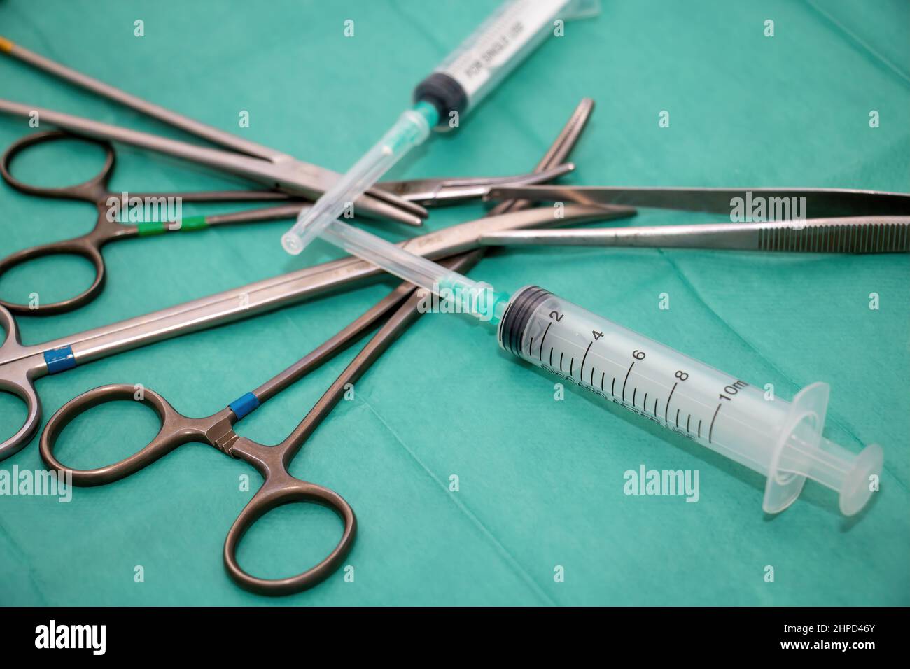 Sterilized surgical instrument on green fabric background. Surgeon doctor stainless steel tool, forceps, needle holder or driver, pincer, scissor and Stock Photo