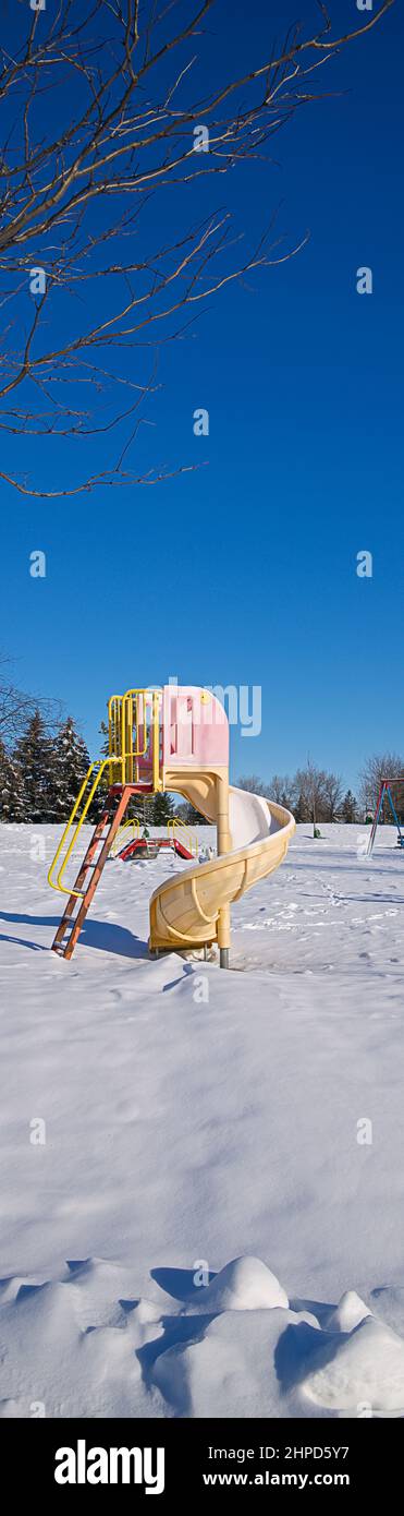 Panoramic vertical web banner of the Slide - play equipment covered with snow n the public park.  Vertical web banner background photo. Stock Photo