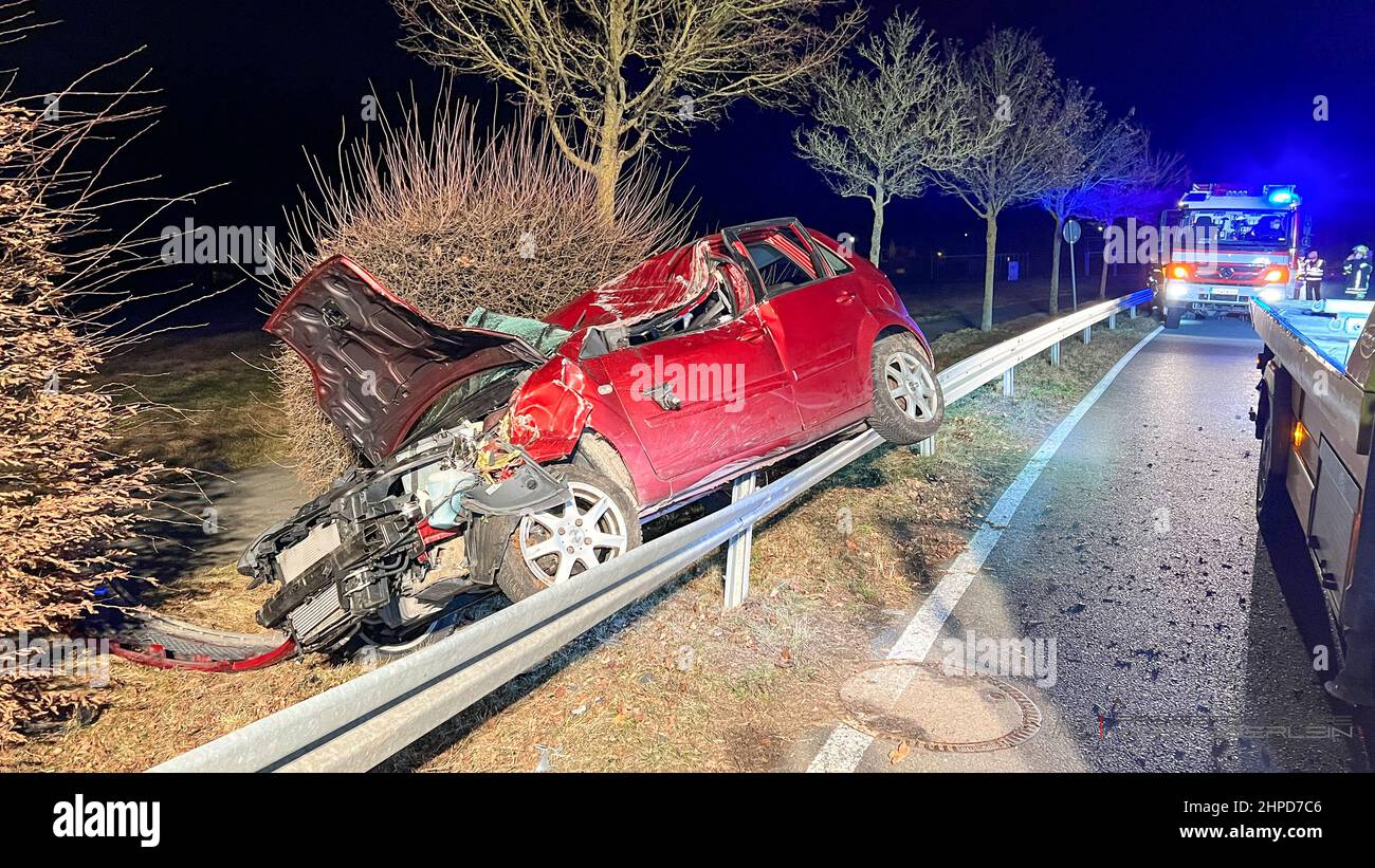 Erlangen, Germany. 20th Feb, 2022. A car wreck hangs on a guardrail. An 83-year-old female driver crashed her car into a tree in Erlangen and was seriously injured. According to initial findings, the driver ran off the road to the left in a right-hand bend. The car probably hit the guard rail, then crashed into a tree and finally came to rest on the guard rail, badly damaged. Credit: ---/vifogra/dpa/Alamy Live News Stock Photo