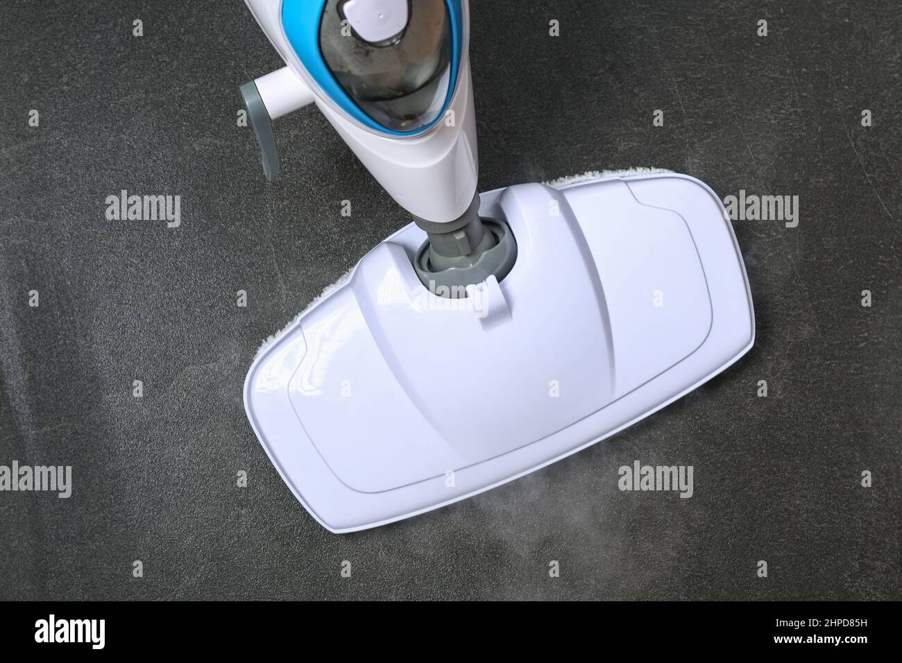 A man washes black porcelain stoneware with a steam mop. Killing germs