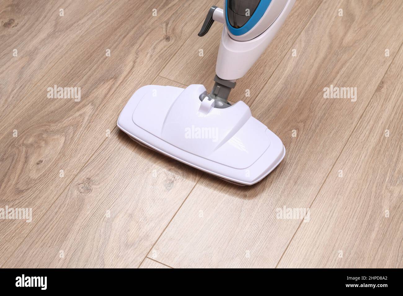 A man washes laminate flooring with a steam mop. Killing germs, clean