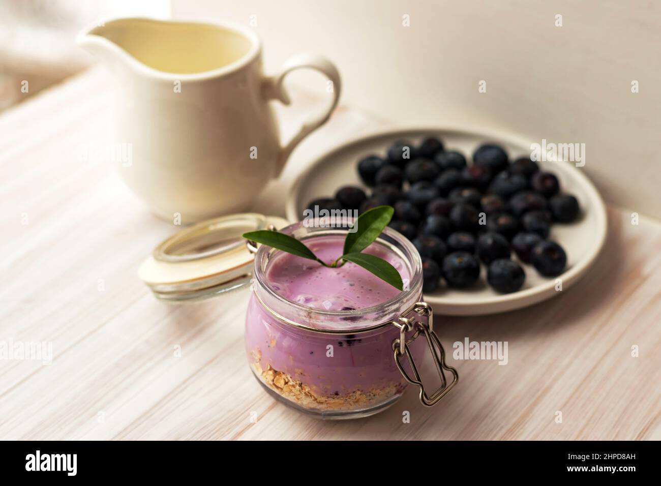 Oat flakes granola or muesli with homemade yogurt smoothie, fresh blueberry and ceramic jug milk Stock Photo