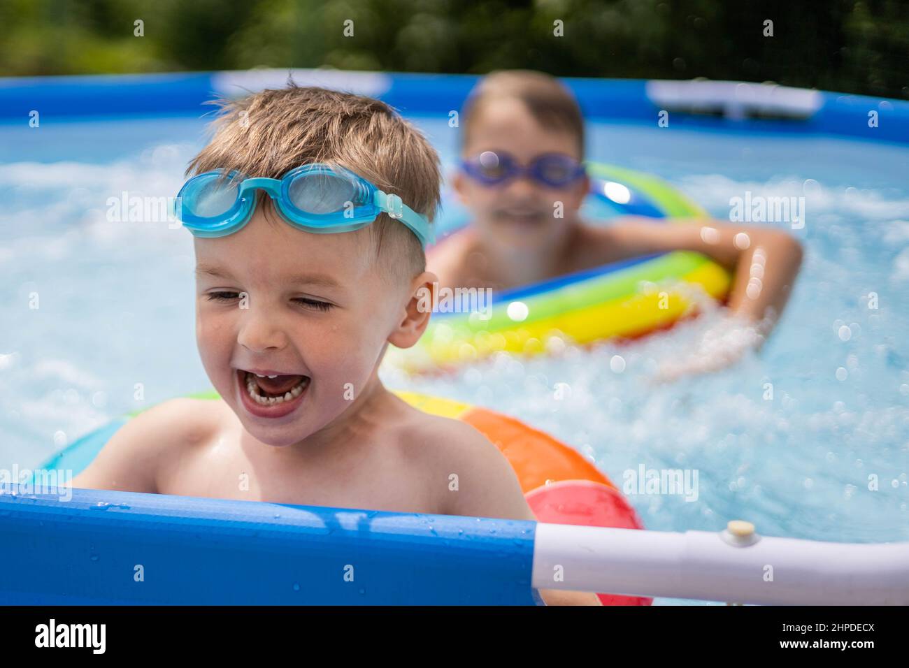 Two boys brothers in the outdoor outdoor pool near the house swim and