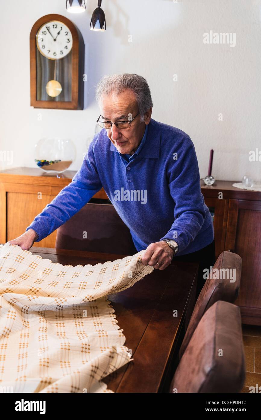 Grandfather putting the tablecloth on the table for eating Stock Photo