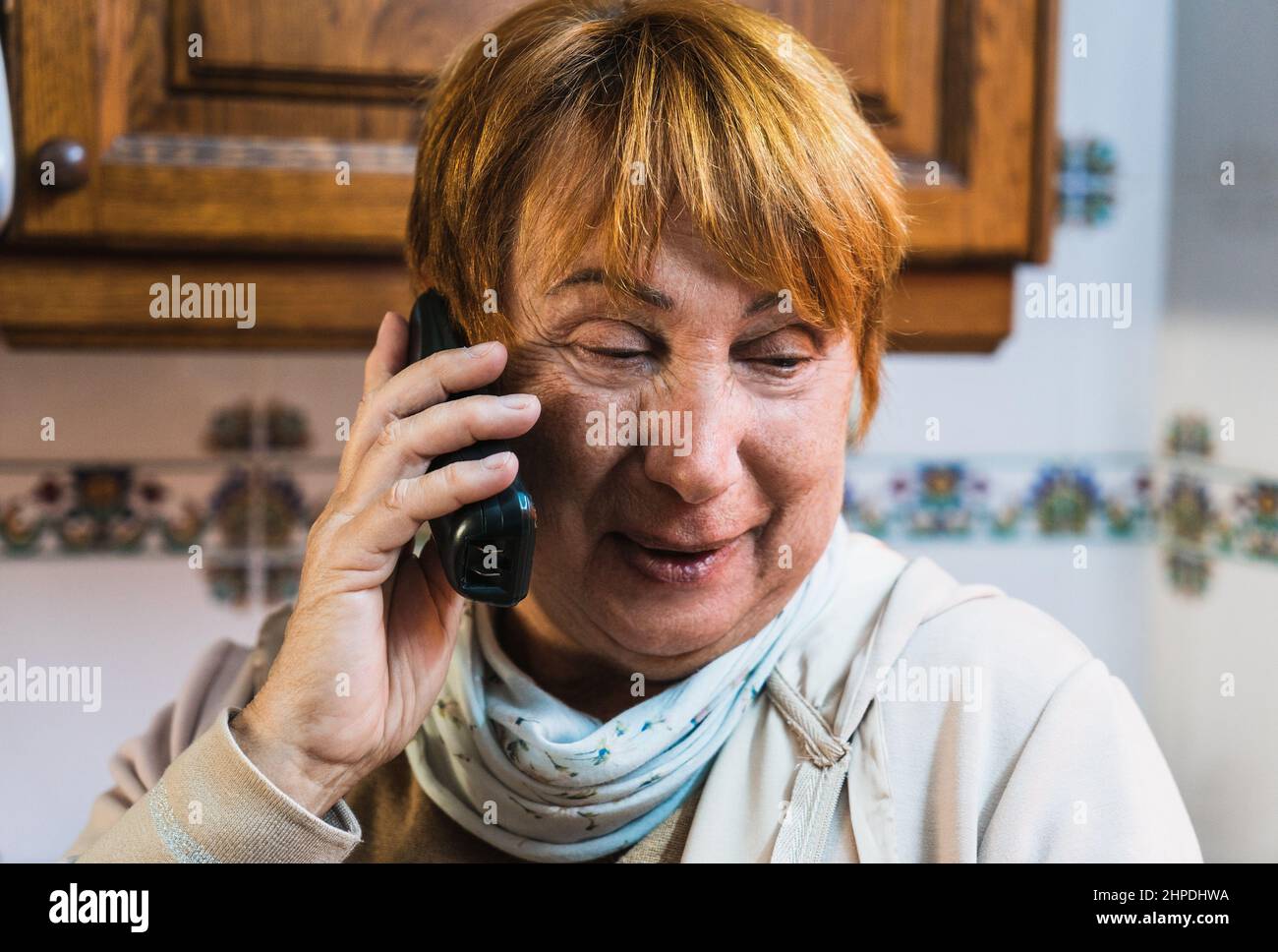 Caucasian Grandmother talking phone in kitchen smiling Stock Photo - Alamy