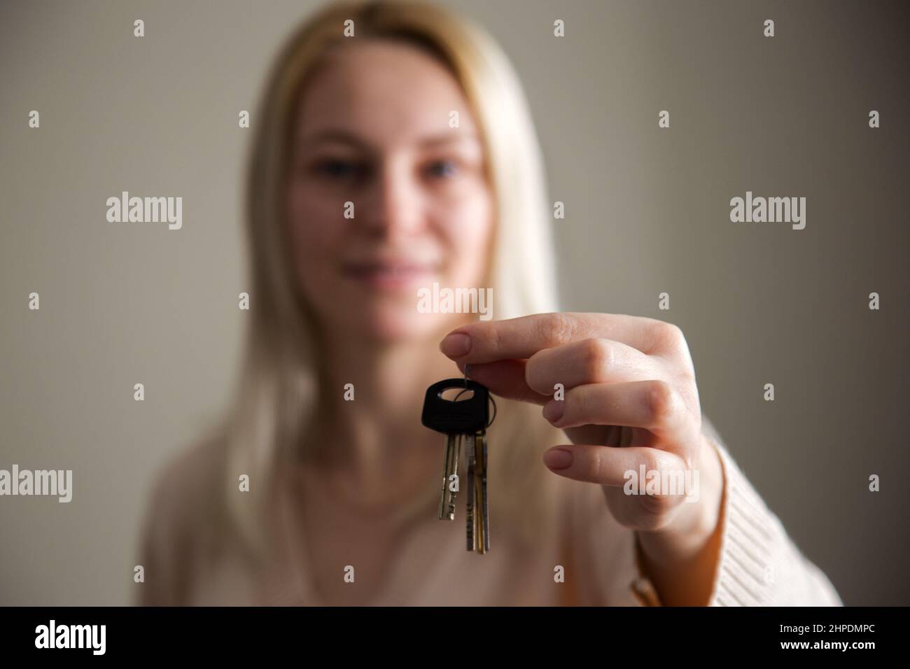 Young woman holding the keys to a new house. Moving to your own home ...