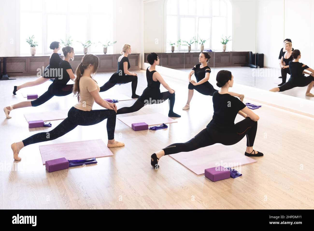 Five Dancer Girls Warming Up With Stretching Exercises For Flexibility During Class In White