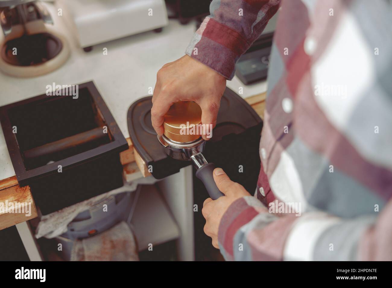 Barista pressing ground coffee into portafilter with tamper Stock Photo