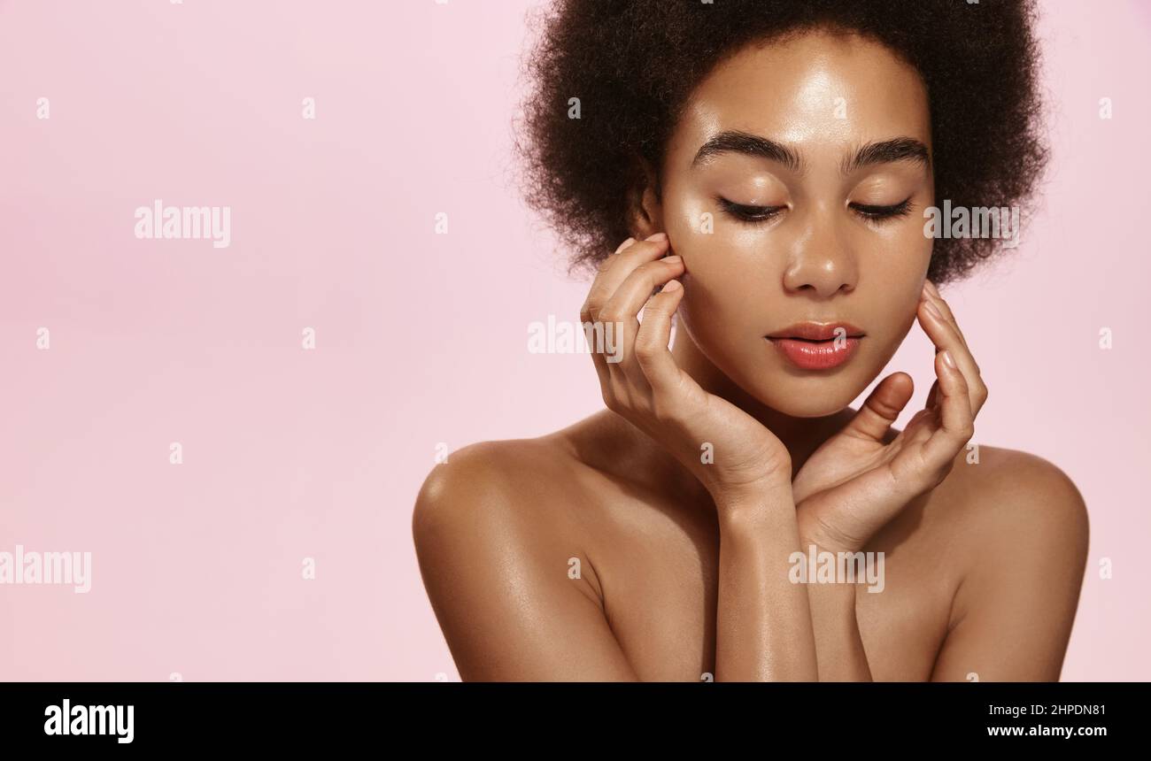 Young african american woman applying soft skin care cream on her body