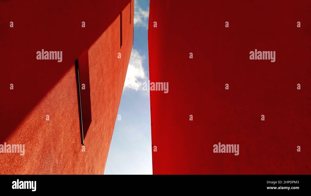 Two orange symmetrical walls of the house facing the sky and clouds in the form of a tunnel. Stock Photo