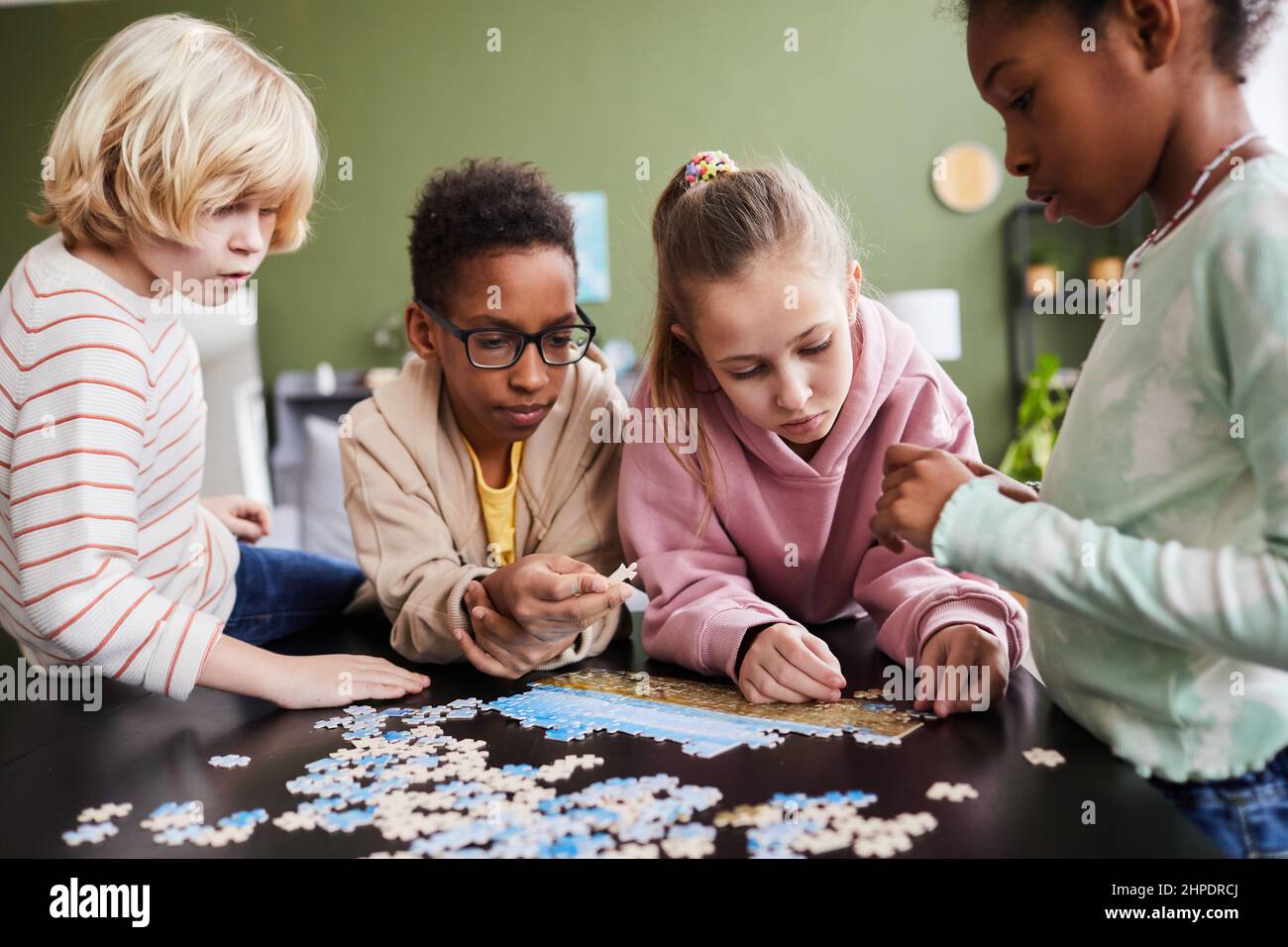 Portrait of diverse group of children playing with puzzle game indoors