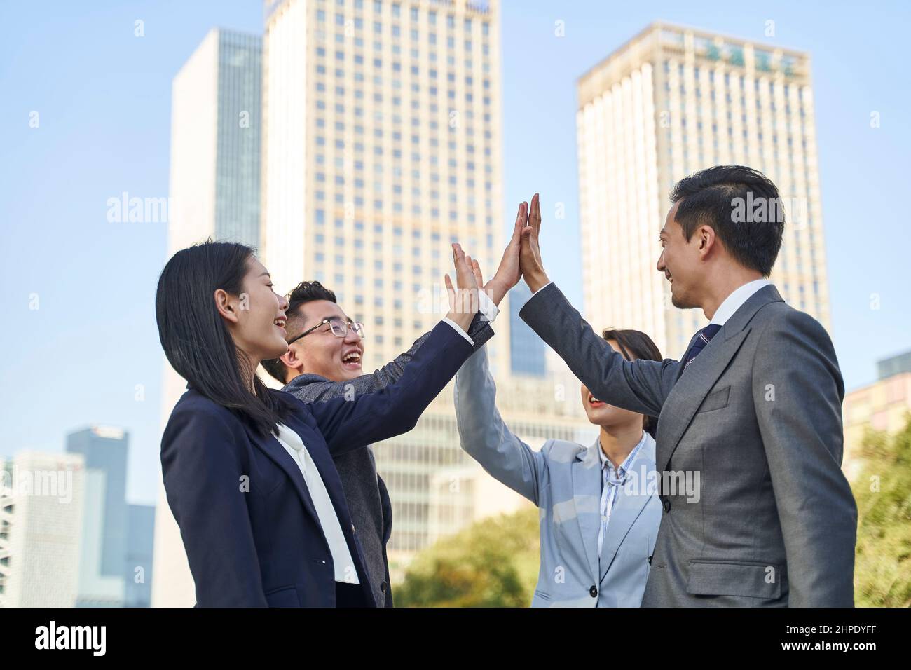 asian business people celebrating success by exchanging high fives Stock Photo