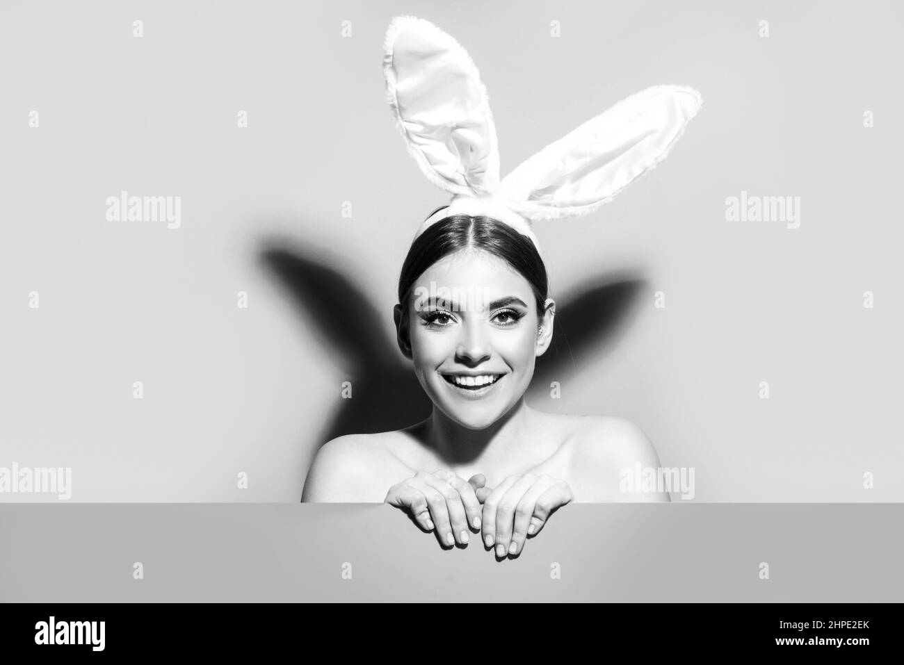 Smiling young woman wearing pink easter bunny ears isolated on pink. Stock Photo
