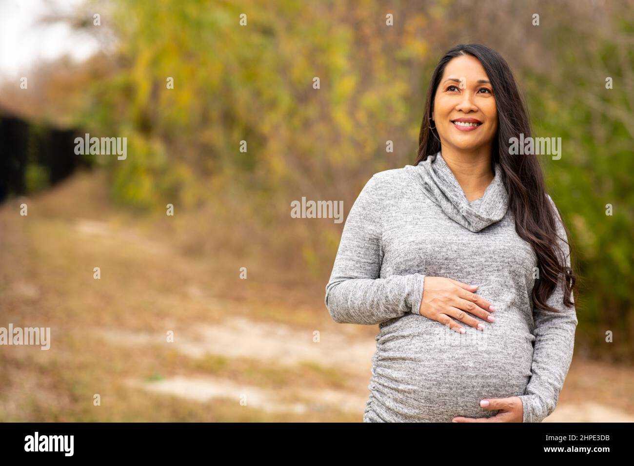 Happy Asian pregnant woman holding her stomach Stock Photo - Alamy