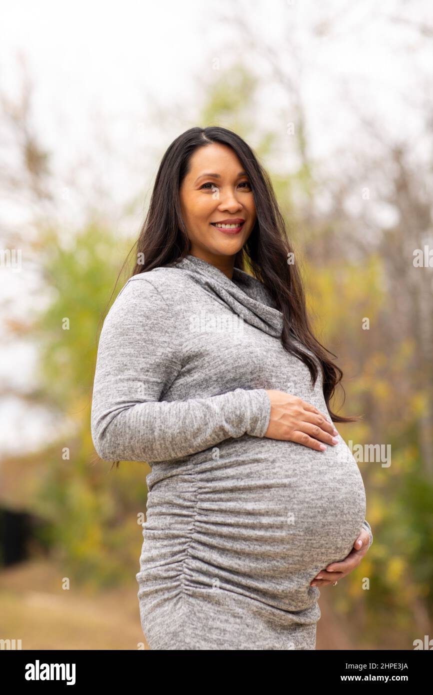 Happy Asian pregnant woman holding her stomach Stock Photo - Alamy